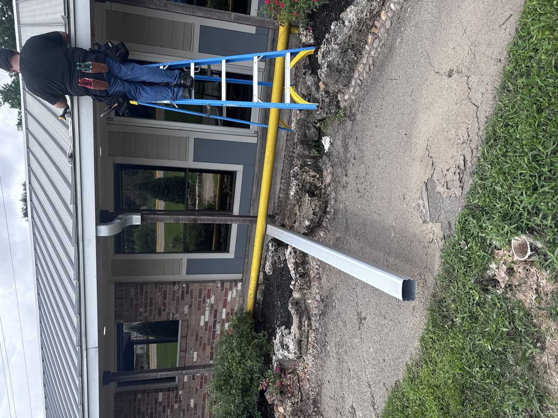 Installer on ladder mid gutter and downspout installation in Conroe, TX